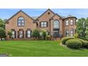 Charming brick home with a lush green lawn and mature trees at 3835 Hickory Branch Trl, Suwanee, GA 30024