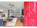 Staged living room boasts hardwood floors, ceiling fan, and a view of the kitchen; entering through the red front door at 4653 Ridgewood Dr, Forest Park, GA 30297