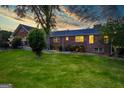 Exterior view of the home's backyard featuring a lush lawn and mature trees, set against a colorful sunset at 3700 Tom Brewer Road, Loganville, GA 30052