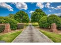 Long paved driveway bordered by manicured greenery, leading to a secluded property under a bright sky at 3700 Tom Brewer Road, Loganville, GA 30052