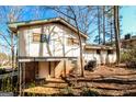 View of the back of the home with a covered patio and brick foundation, surrounded by mature trees at 2571 Beech St, Morrow, GA 30260