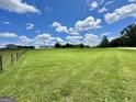 Spacious backyard with vibrant green lawn, partially fenced, under a beautiful sky with fluffy clouds at 3014 Bowdon Tyus Rd, Bowdon, GA 30108
