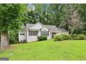 Well-kept white home with lush green lawn, mature trees, and a charming design at 345 Sharon Dr, Fayetteville, GA 30214