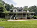 Charming two-story home with a large wraparound porch and a lush green lawn at 3970 Governors Cir, Loganville, GA 30052
