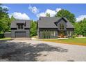 Beautiful modern farmhouse exterior with a detached garage and a gravel driveway surrounded by lush greenery at 500 Happy Hollow Rd, Villa Rica, GA 30180