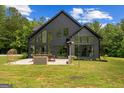 Modern black home with large windows and patio seating area with views of a well manicured lawn at 500 Happy Hollow Rd, Villa Rica, GA 30180