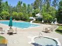 A well-maintained community pool featuring a slide, hot tub, lounge chairs, and umbrella-covered tables at 56 American Walk, Peachtree City, GA 30269