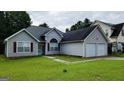 Inviting gray home with an attached garage and a lush green lawn at 5502 Sapphire Cir, Ellenwood, GA 30294