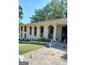 Side view of home with unique, arched porch openings and mature trees at 6266 Auburn Dr, Riverdale, GA 30296