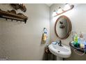 Cozy powder room featuring a pedestal sink, decorative mirror, and stylish wall decor at 105 N River Dr # G, Sandy Springs, GA 30350