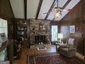 Inviting living room with a brick fireplace, wood-paneled walls, and a vaulted ceiling with exposed beams at 529 Valley Woods Se Cir, Conyers, GA 30094