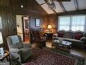 Cozy living room featuring wood paneling, a ceiling fan, and comfortable seating with an adjacent dining room view at 529 Valley Woods Se Cir, Conyers, GA 30094