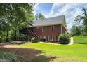 View of the brick home's back exterior featuring a wooden deck and backyard with green lawn at 172 Sam Solomon Rd, Locust Grove, GA 30248