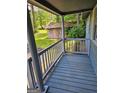 Inviting porch view featuring wood flooring, grey railings, and exterior views of greenery and a shed at 602 Mccurdy Rd, Villa Rica, GA 30180
