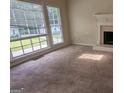 Bright living room featuring large windows, neutral carpet, fireplace and decorative mantel at 9230 Melody Sw Cir, Covington, GA 30014