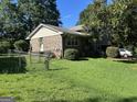 Brick home with a well-maintained lawn, complemented by lush bushes and a classic chain-link fence at 90 Cabriolet Trail, Mcdonough, GA 30253