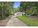 A house with a long driveway surrounded by trees, enhancing its curb appeal and natural setting at 118 Whitfield Run, Peachtree City, GA 30269