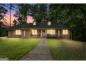 Dusk view of a brick home featuring a quaint front porch, two dormers, and a well-manicured front lawn at 1290 Shadowlawn Ne Dr, Conyers, GA 30012