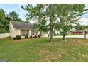 Residential home featuring a lush green lawn, mature trees, and manicured bushes along the front at 2898 Cedar Trace Dr, Ellenwood, GA 30294