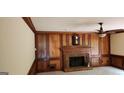 Cozy living room featuring wood paneling, a ceiling fan, a decorative brick fireplace, and a wall clock at 3626 Lone Indian Trl, Marietta, GA 30066