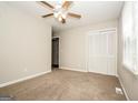 Comfortable bedroom featuring a ceiling fan, plush carpeting, and ample closet space at 6194 Golden Meadow Court Ct, Riverdale, GA 30296