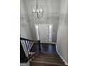 Elegant entryway with dark wood stairs, modern chandelier and bright view through the front door at 946 Creek Run Pl, Temple, GA 30179