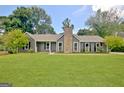 Charming single-story home with a stone chimney, complemented by a lush green lawn and mature trees at 110 Chesterfield Ct, Fayetteville, GA 30214