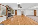 Bright, open living room showcasing hardwood floors, a ceiling fan, and a stone fireplace, perfect for entertaining at 1189 E Fayetteville Rd, Riverdale, GA 30296