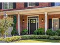 Inviting front entryway with black door, sidelights, brick facade, manicured landscaping and address number at 4729 Woodland Brook Se Ct, Atlanta, GA 30339