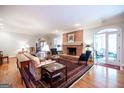 Bright living room boasts hardwood floors, a brick fireplace, a comfortable seating arrangement, and ample natural light at 3030 Spalding Dr, Sandy Springs, GA 30350