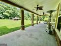 Covered patio with ceiling fans, stone-wrapped columns, and a spacious green backyard with playground at 345 Peaceful Way, Fayetteville, GA 30214