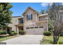 Charming home featuring a stone facade, a two-car garage, and lush landscaping at 2780 Lakeview Walk, Decatur, GA 30035