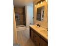 Modern bathroom featuring a double sink vanity, wood-look cabinets, and a shower-tub combo with glass door at 1053 Metropolitan Parkway Southwest Sw Pkwy, Atlanta, GA 30310