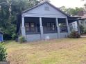 Quaint gray bungalow showcasing a welcoming front porch, carport, and well-established landscaping at 1053 Metropolitan Parkway Southwest Sw Pkwy, Atlanta, GA 30310