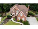 Aerial view of a landscaped home with brick exterior, manicured lawn, and spacious driveway at 200 Long Needle Ct, Sugar Hill, GA 30518