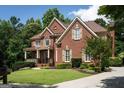 Lovely brick home with lush landscaping, mature trees, and a welcoming front porch at 200 Long Needle Ct, Sugar Hill, GA 30518