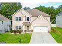 Tan, two-story home with a two-car garage, and landscaped front yard at 232 Shelton Cir, Temple, GA 30179