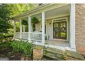 Inviting front porch with white columns, a cozy seating area, and lush greenery, perfect for relaxing outdoors at 1788 River Bluff Vw, Duluth, GA 30097
