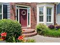 Close-up front door featuring a decorative wreath, brick stairs, and vibrant flowers, enhancing its inviting charm at 5418 Amity Dr, Powder Springs, GA 30127