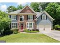 Attractive two-story home showcasing a brick facade, complemented by a well-maintained lawn and an attached two-car garage at 5418 Amity Dr, Powder Springs, GA 30127