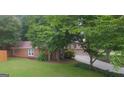Well-manicured lawn and landscaping surround a brick home with an asphalt driveway and mature trees at 11940 Wexford Club Dr, Roswell, GA 30075