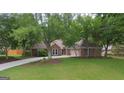 Beautifully landscaped front yard with lush grass and mature trees framing the brick home and driveway at 11940 Wexford Club Dr, Roswell, GA 30075