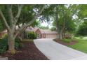 Brick home featuring a long driveway, well-maintained landscaping, mature trees, and a two-car garage at 11940 Wexford Club Dr, Roswell, GA 30075