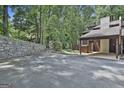 Wide view of the parking area and a stone retaining wall surrounded by mature trees and landscaping at 36 Cobblestone Crk, Peachtree City, GA 30269