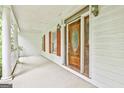 Inviting front porch with white columns, red window shutters, and an ornate wooden front door at 936 Bo Bo Banks Rd, Grantville, GA 30220