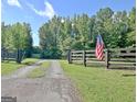 Property entrance with dark wooden fence, gravel driveway, and American flag at 5187 Lower Fayetteville Rd, Sharpsburg, GA 30277