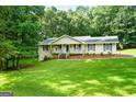 Inviting single-Gathering home with a charming front porch, complemented by a lush green lawn and mature trees at 185 Downybrook Ln, Fayetteville, GA 30215