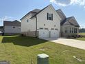 Side view of a two-story home with a two-car garage, showcasing the well-manicured lawn and modern design at 13709 Whitman Ln, Covington, GA 30014