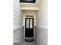 The front door is black with two glass panels, framed by brick and white siding at 13709 Whitman Ln, Covington, GA 30014