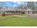 Inviting brick home showcasing a green metal roof, covered porch, well-maintained lawn, and a convenient two-car garage at 81 Bowers Rd, Moreland, GA 30259